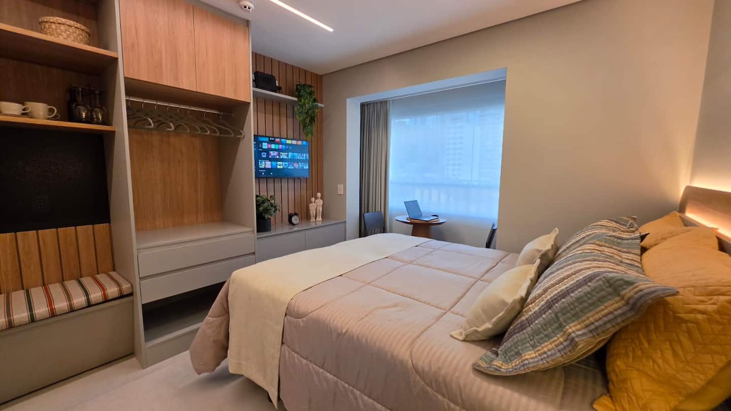 Quarto visto do pé da cama, com Smart TV e closet